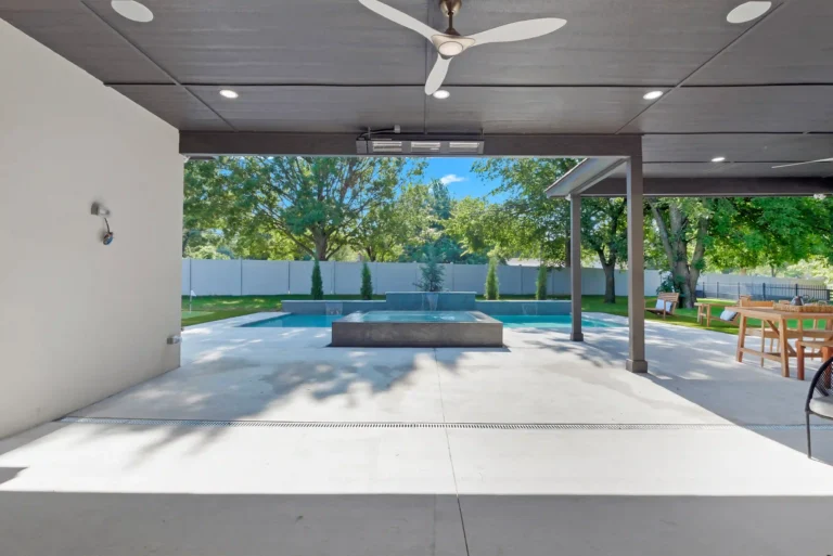 backyard concrete patio of rutd home with pool and outdoor living area